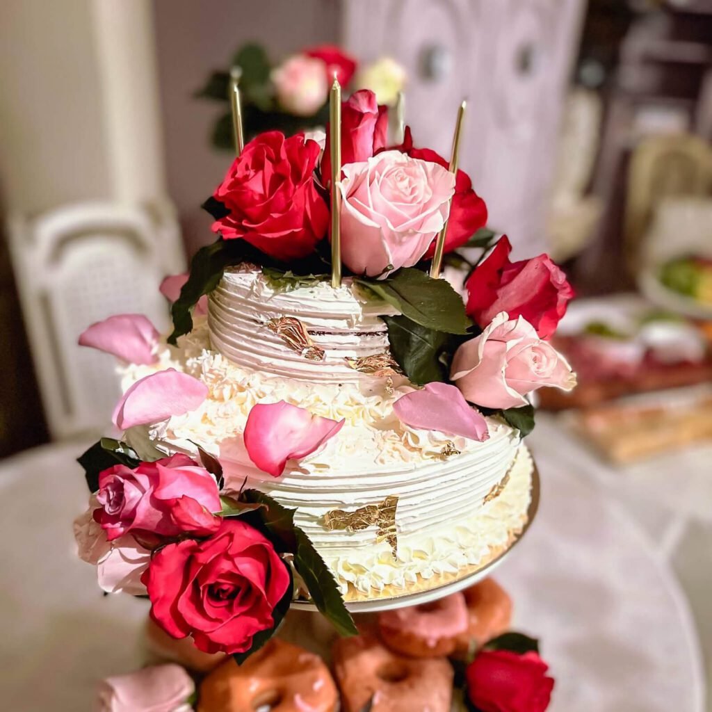 A zoomed in on a beautiful cake decorated with red roses.