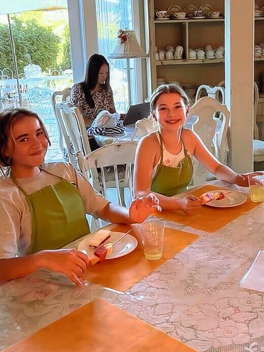 Two girls pose for a photo eating their snacks on their cake decorating party.
