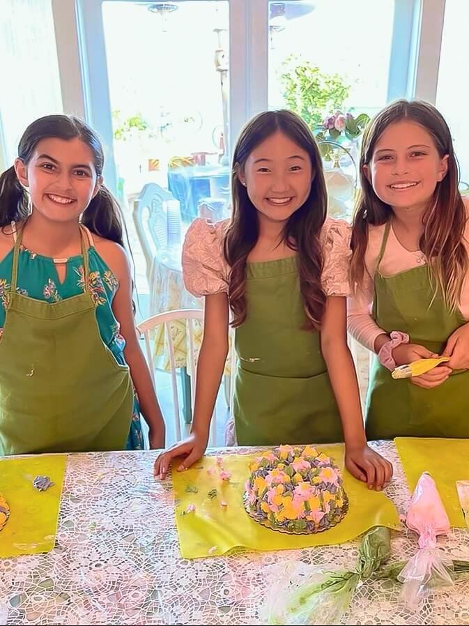 Three girls smile and pose for a photo after they're creating their cake.