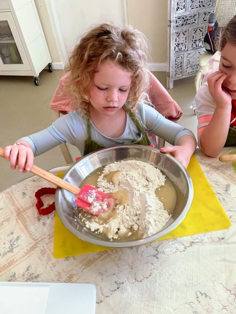 A little girl works on her dough, getting ready to cook.
