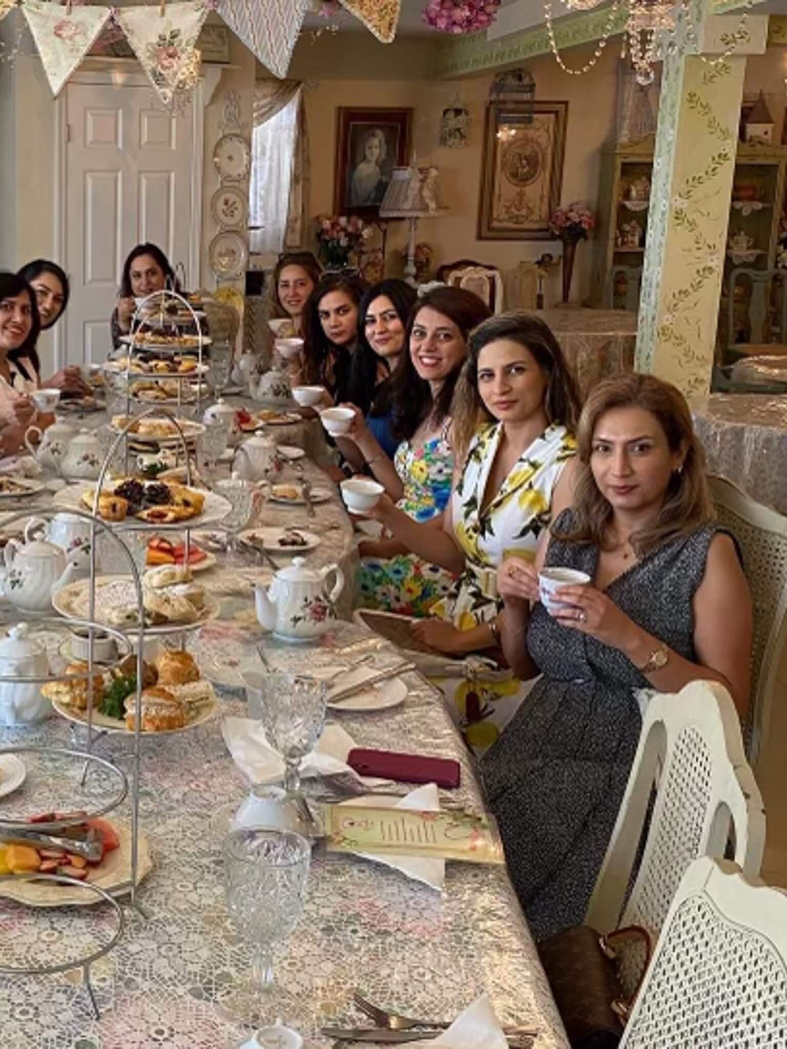 A group of women sit at a table enjoying their tea and pastries.