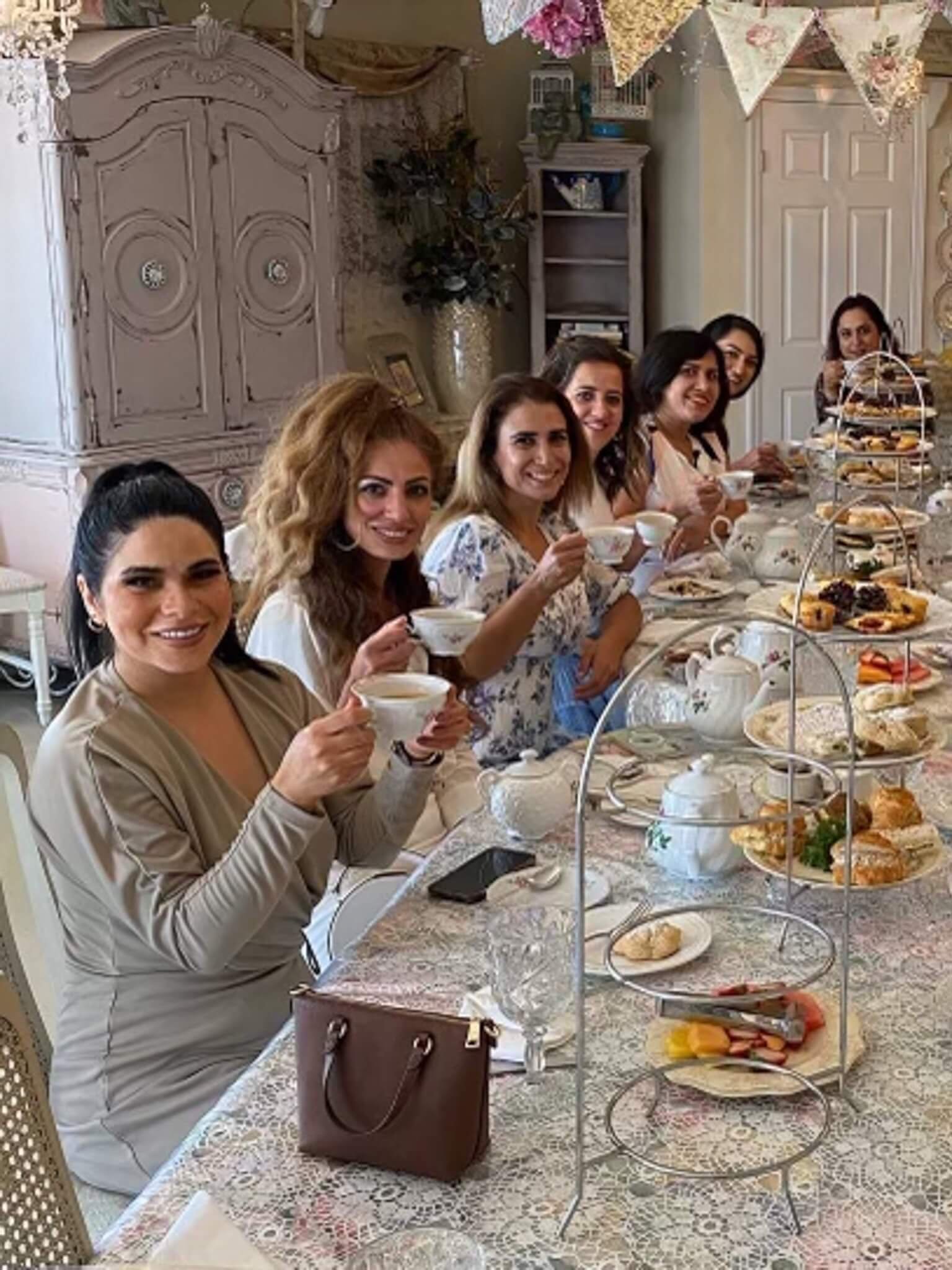 A group of women sit at a table enjoying their tea and pastries.